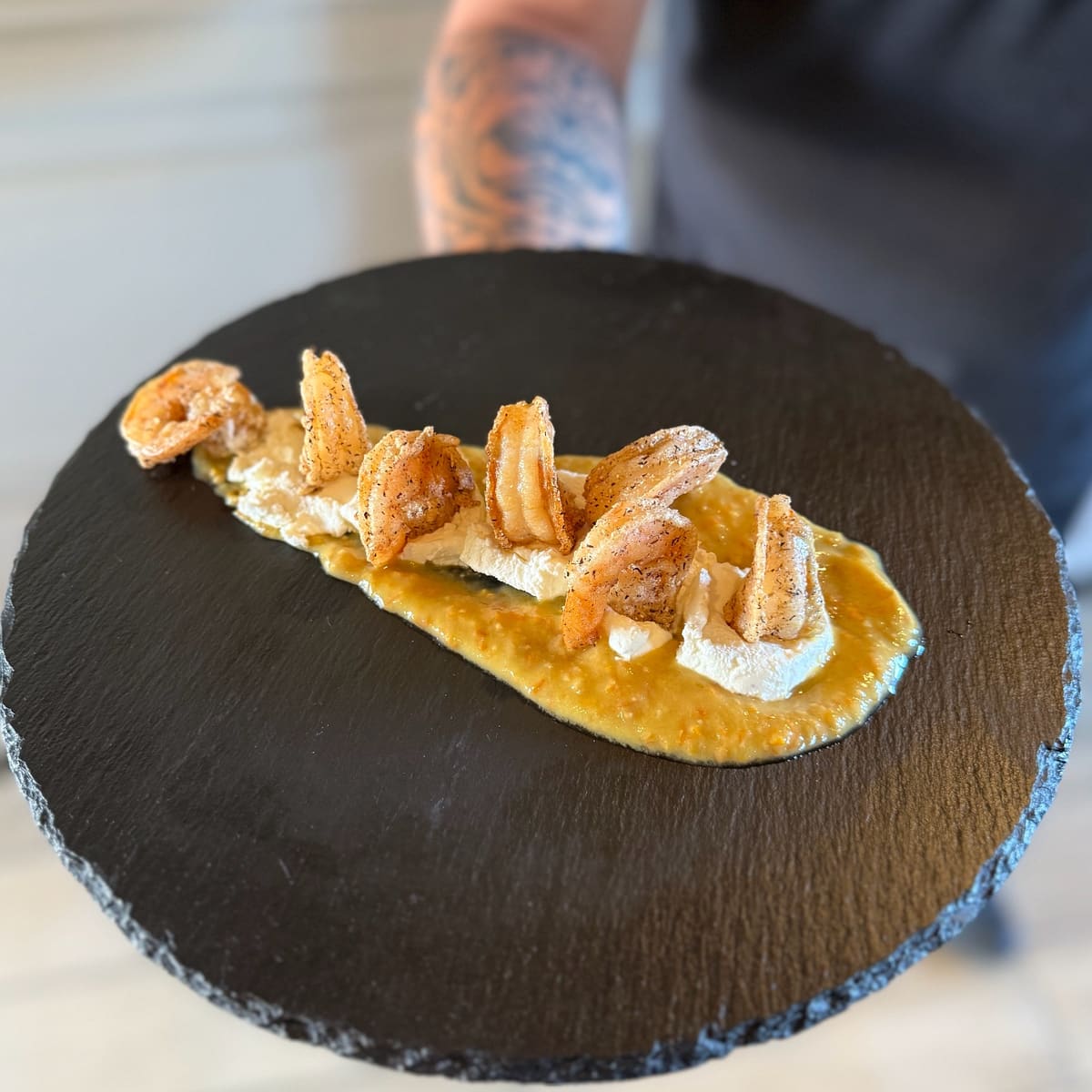 Gamberi croccanti su crema, in un piatto di ardesia
